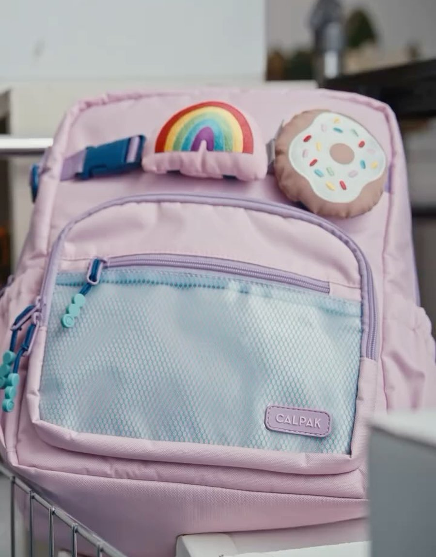 Calpak spot — a pink kids' backpack with rainbow and doughnut charms
